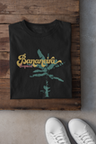 Bananeira (banana tree) t-shirt in black folded on a wooden table next to white shoes