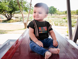 Little boy wearing a black Robo DJ t-shirt while sitting on a picnic table