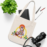 Missy Girl Organic Canvas Tote in natural color that shows a cute doll like girl picking flowers on a table next to a camera