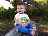 Little boy wearing a cozy little beep t-shirt sitting on a bench