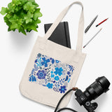Azul Flowers Organic Canvas tote bag in natural color canvas with a print of blue azul style flowers on a table with a camera