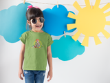 Little girl wearing a green Missy Girl todder t-shirt in front of paper clouds and the sun while wearing round sun glasses