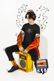 Louliibot tee with cute robot DJ graphic in the color black worn by a teen sitting on an ainimated speaker with music animation things around him 