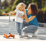 little girl wearing a cozy little beep t-shirt with her mom and her orange scooter