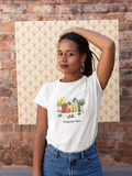Young women wearing a white tropical chic t-shirt in front of a brick wall