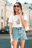 Desert Cactus Unisex tee with a cactus graphic in the color white worn by a young lady talking on a phone